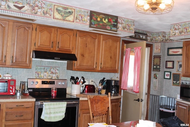 kitchen featuring light countertops, decorative backsplash, under cabinet range hood, and stainless steel appliances