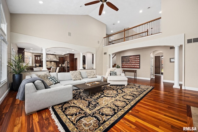 living area with a ceiling fan, visible vents, ornate columns, and arched walkways