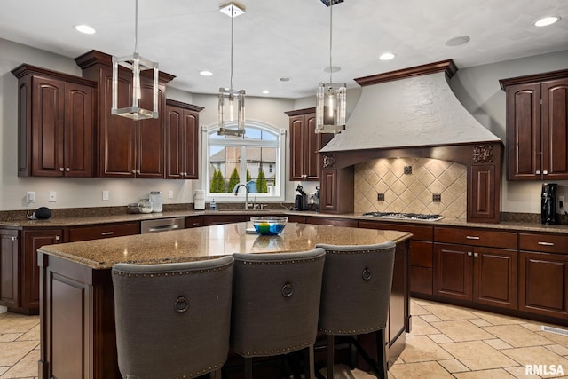 kitchen featuring stone tile floors, dark stone countertops, a kitchen island, and premium range hood