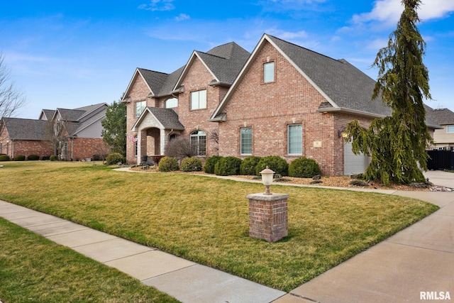 traditional home featuring brick siding, a shingled roof, and a front lawn
