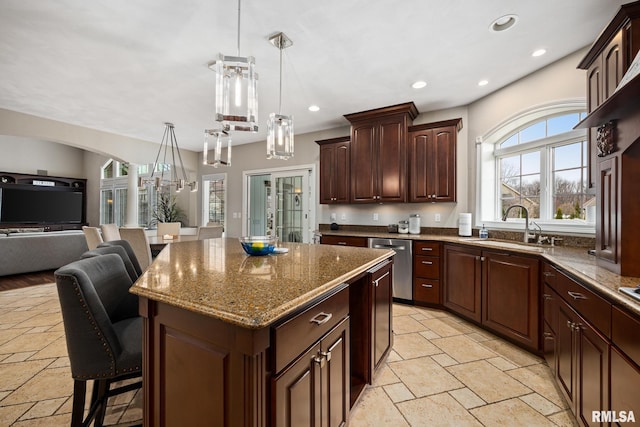 kitchen featuring a kitchen island, open floor plan, a breakfast bar area, stone tile floors, and a sink