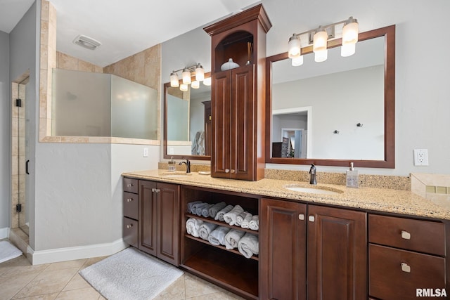 bathroom featuring visible vents, a shower stall, double vanity, tile patterned floors, and a sink