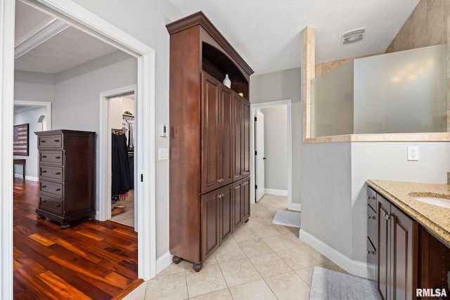 full bathroom with tile patterned floors, visible vents, vanity, baseboards, and a spacious closet