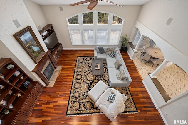 living area with arched walkways, lofted ceiling, wood finished floors, and a ceiling fan