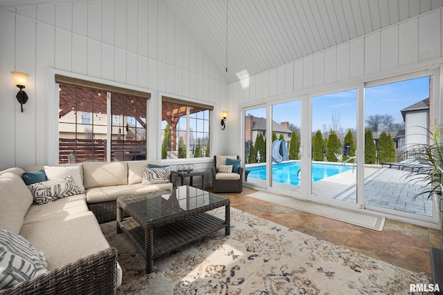 sunroom featuring high vaulted ceiling, outdoor lounge area, and stone finish floor