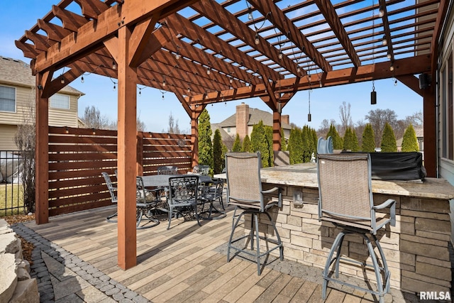 deck with outdoor dry bar, a pergola, and fence