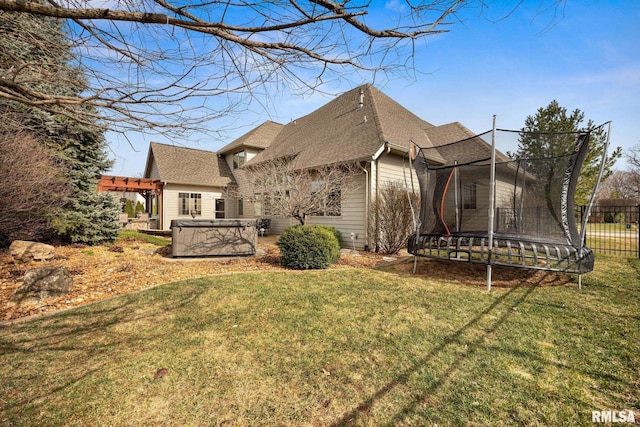 exterior space featuring a lawn, a pergola, a trampoline, a shingled roof, and a hot tub