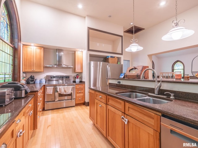 kitchen featuring visible vents, a towering ceiling, appliances with stainless steel finishes, a sink, and wall chimney range hood