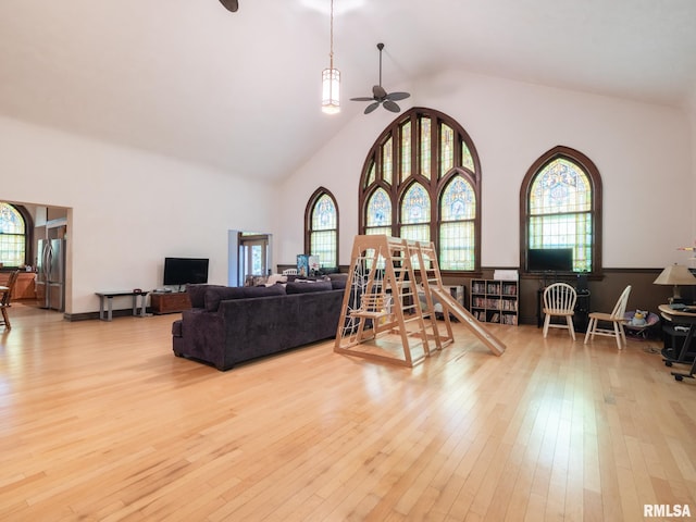 living room with ceiling fan, high vaulted ceiling, and light wood finished floors