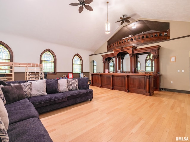 living area featuring a ceiling fan, high vaulted ceiling, baseboards, and light wood-type flooring