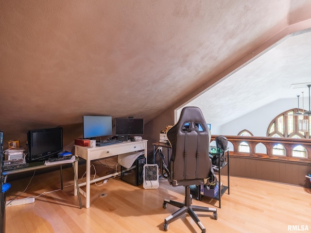 office space featuring wainscoting, a textured ceiling, vaulted ceiling, and wood finished floors