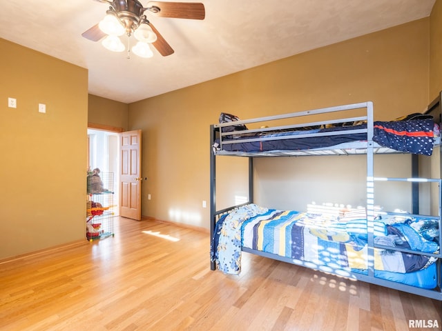 bedroom featuring baseboards, wood finished floors, and a ceiling fan