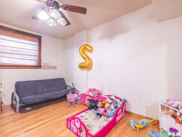 recreation room featuring baseboards, ceiling fan, and wood finished floors