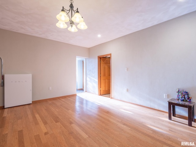 unfurnished room with light wood finished floors, baseboards, and a chandelier
