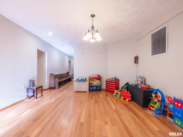 recreation room with a chandelier and light wood finished floors