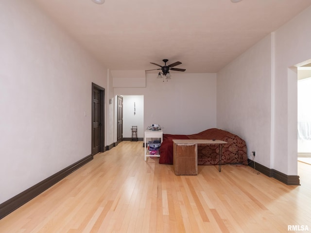 living area with light wood finished floors, baseboards, and ceiling fan