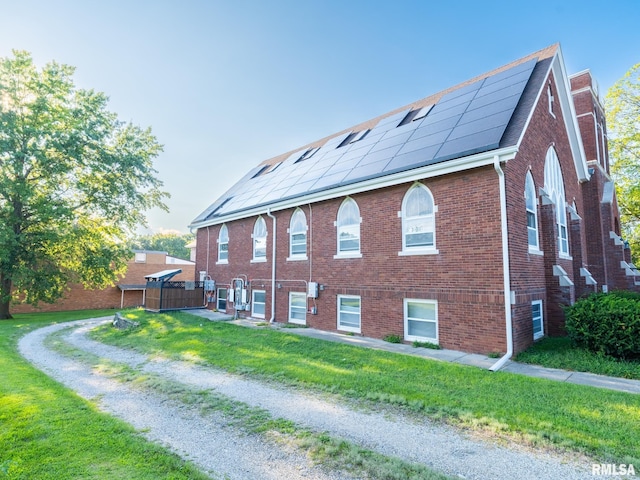 view of home's exterior featuring solar panels, a shingled roof, brick siding, and a yard
