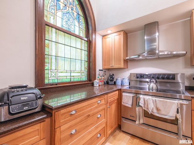 kitchen featuring electric range, plenty of natural light, dark stone countertops, and wall chimney exhaust hood