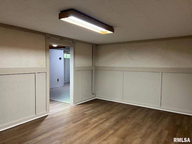 finished below grade area with a decorative wall, wood finished floors, and wainscoting