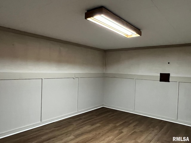 empty room with a decorative wall, wood finished floors, and wainscoting
