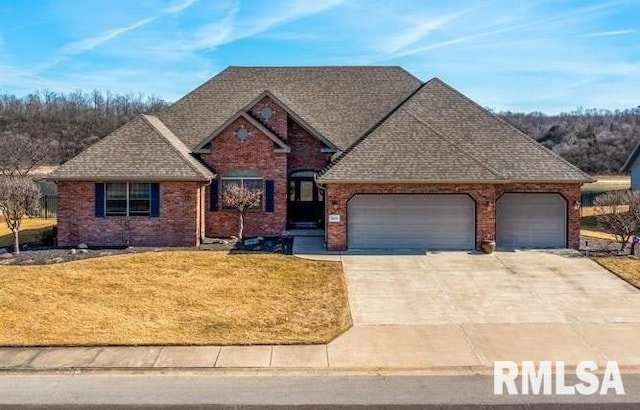 view of front facade with roof with shingles, a front yard, brick siding, a garage, and driveway
