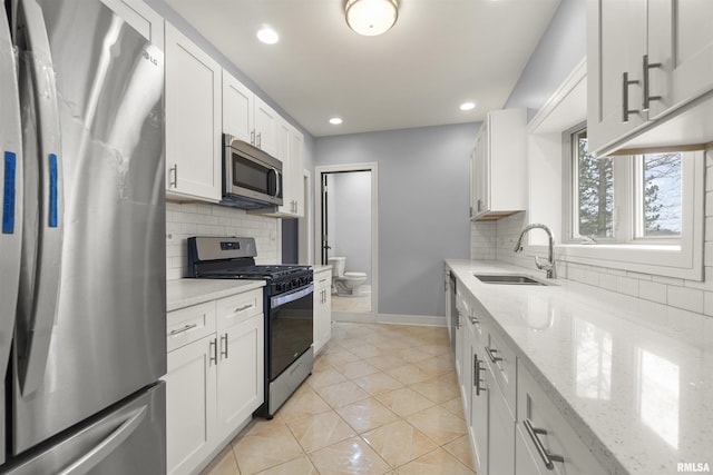 949 NE Glen Oak Ave, Peoria, IL 61603 - kitchen with light tile patterned floors, white cabinets, appliances with stainless steel finishes, a sink, and baseboards