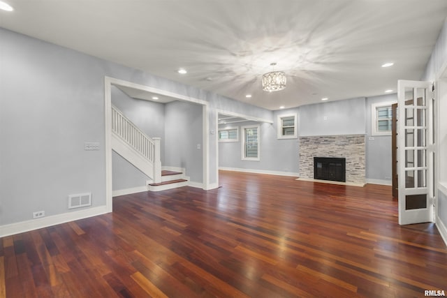 949 NE Glen Oak Ave, Peoria, IL 61603 - unfurnished living room featuring a notable chandelier, baseboards, stairway, visible vents, and wood finished floors