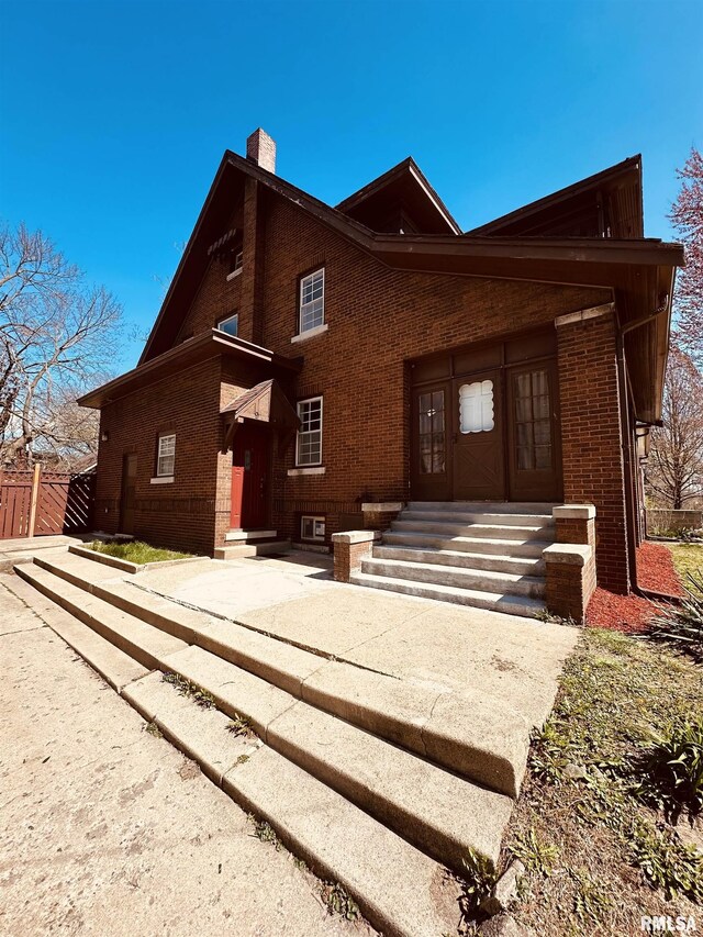 949 NE Glen Oak Ave, Peoria, IL 61603 - view of front facade featuring entry steps, fence, brick siding, and a chimney