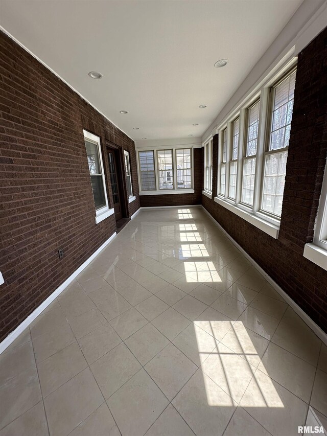 949 NE Glen Oak Ave, Peoria, IL 61603 - unfurnished sunroom featuring baseboards, recessed lighting, tile patterned flooring, and brick wall