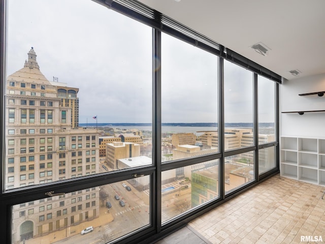 unfurnished sunroom featuring a city view, plenty of natural light, and visible vents