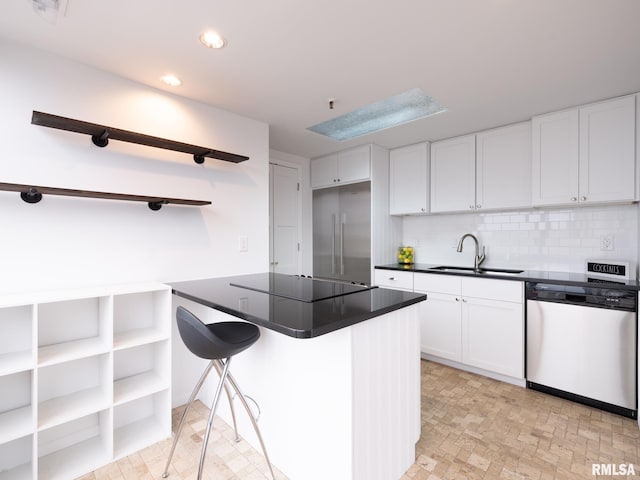 kitchen with decorative backsplash, a sink, dark countertops, white cabinets, and appliances with stainless steel finishes