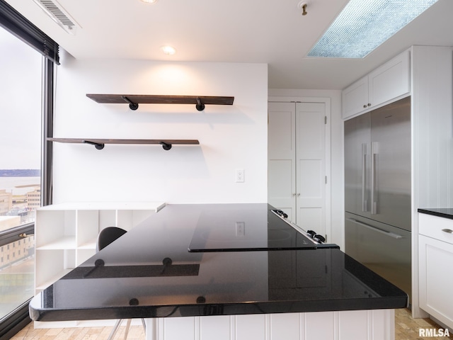 kitchen featuring built in fridge, visible vents, open shelves, and dark countertops