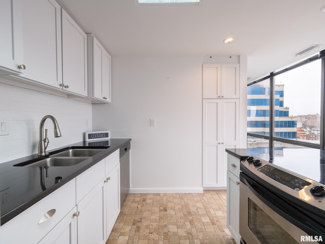 kitchen featuring backsplash, a sink, dark countertops, dishwasher, and white cabinets