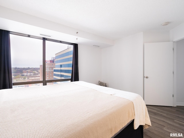 bedroom with visible vents, dark wood-type flooring, and a textured ceiling