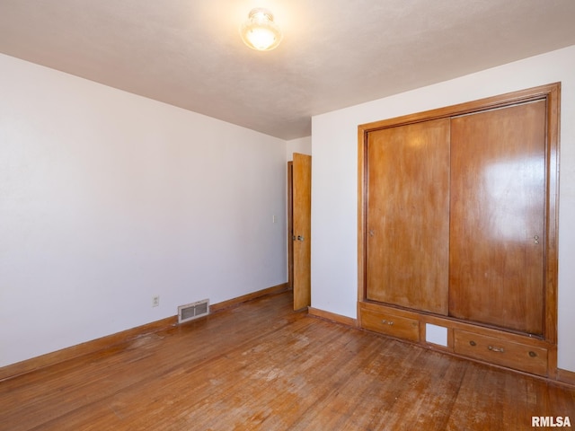 102 S Van Buren St, Lewistown, IL 61542 - unfurnished bedroom with baseboards, visible vents, a closet, and wood-type flooring