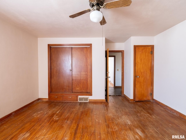102 S Van Buren St, Lewistown, IL 61542 - unfurnished bedroom featuring baseboards, visible vents, a ceiling fan, and wood-type flooring