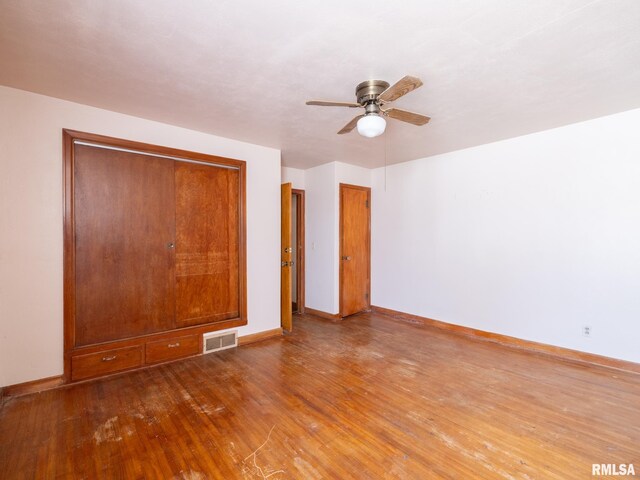 102 S Van Buren St, Lewistown, IL 61542 - unfurnished bedroom with a closet, a ceiling fan, baseboards, visible vents, and hardwood / wood-style floors