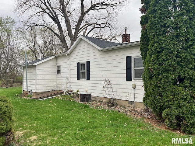view of side of home featuring a yard, central AC unit, crawl space, and a chimney
