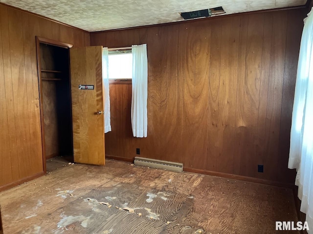 unfurnished bedroom with a baseboard radiator, wooden walls, and baseboards