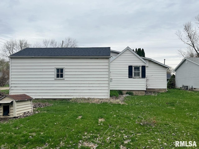 view of side of property featuring a yard and a shingled roof