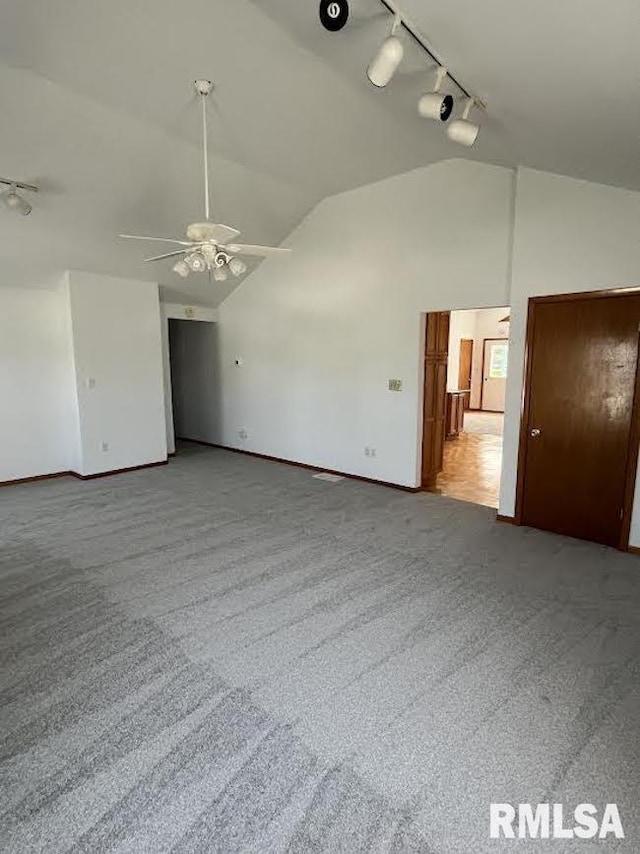 spare room featuring track lighting, vaulted ceiling, carpet floors, baseboards, and a ceiling fan