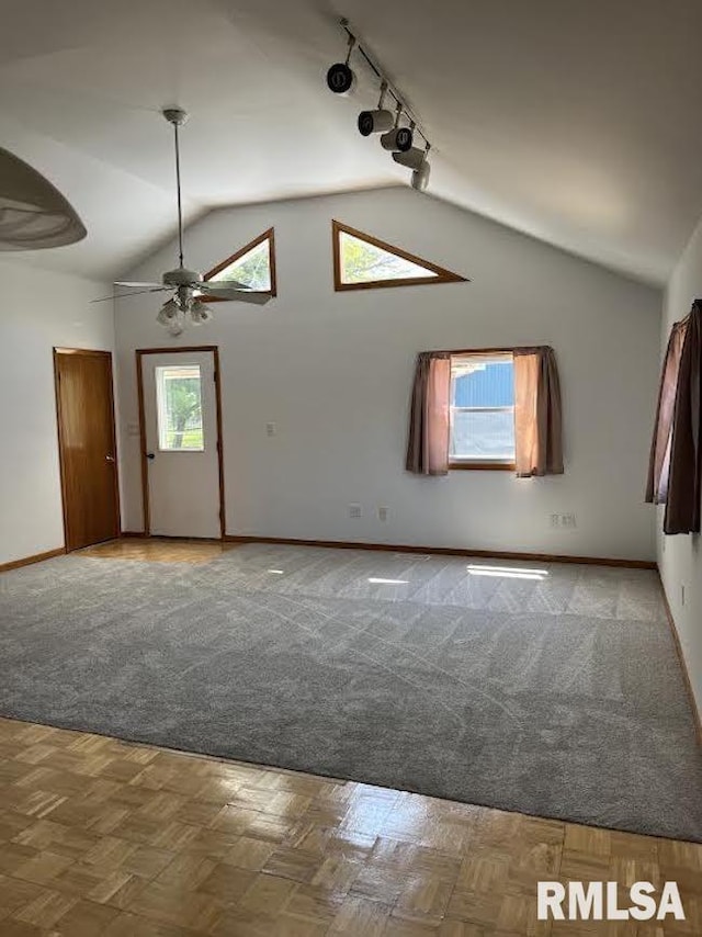 spare room featuring track lighting, lofted ceiling, ceiling fan, and baseboards