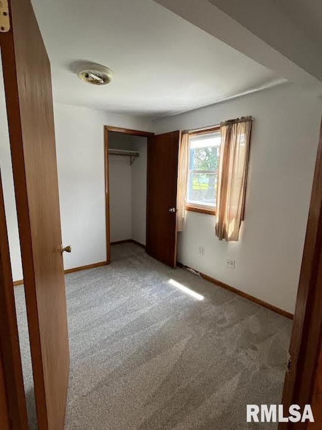 unfurnished bedroom with carpet flooring, baseboards, and a closet