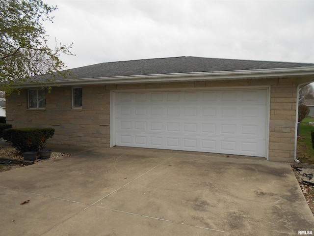 4 Hiel Dr, Bushnell, IL 61422 - view of side of property featuring concrete driveway, a shingled roof, and stone siding
