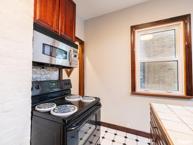 943 NE Glen Oak Ave, Peoria, IL 61603 - kitchen featuring stainless steel microwave, baseboards, black electric range, light floors, and tile countertops