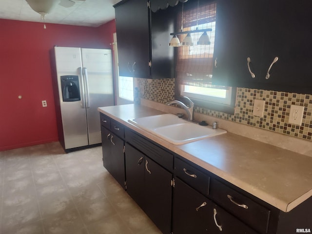 kitchen with plenty of natural light, light countertops, a sink, and stainless steel fridge