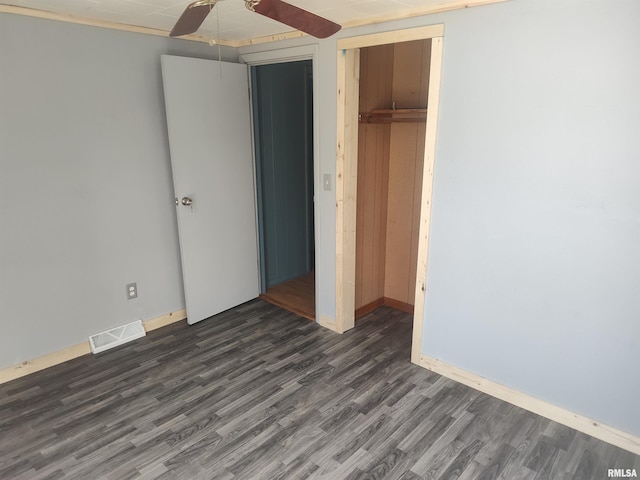 unfurnished bedroom featuring dark wood-style flooring, visible vents, a closet, and baseboards