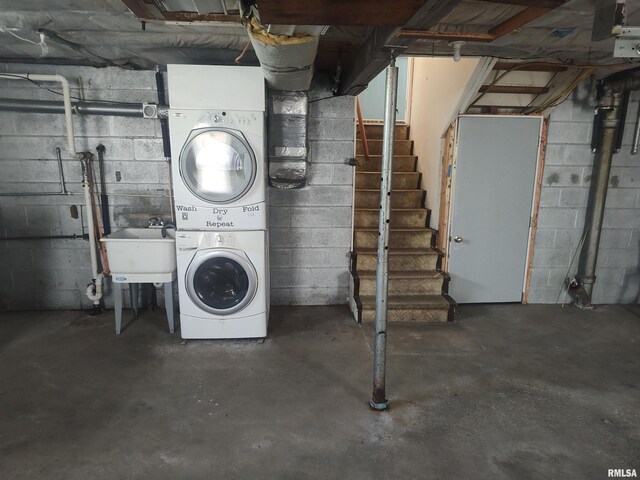 unfinished basement featuring stairs and stacked washer and dryer