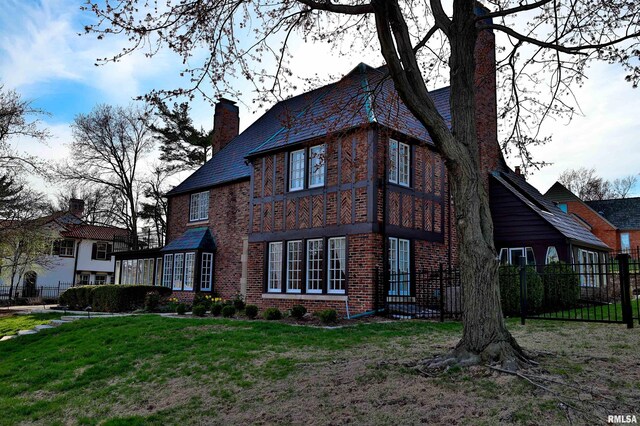 view of side of home with fence, a yard, brick siding, and a chimney