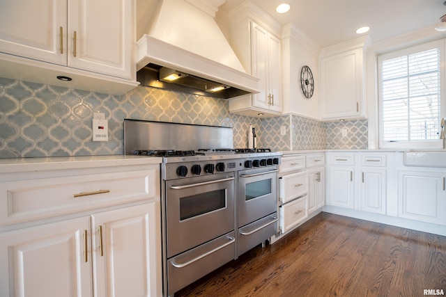kitchen featuring light countertops, dark wood finished floors, white cabinetry, double oven range, and custom range hood